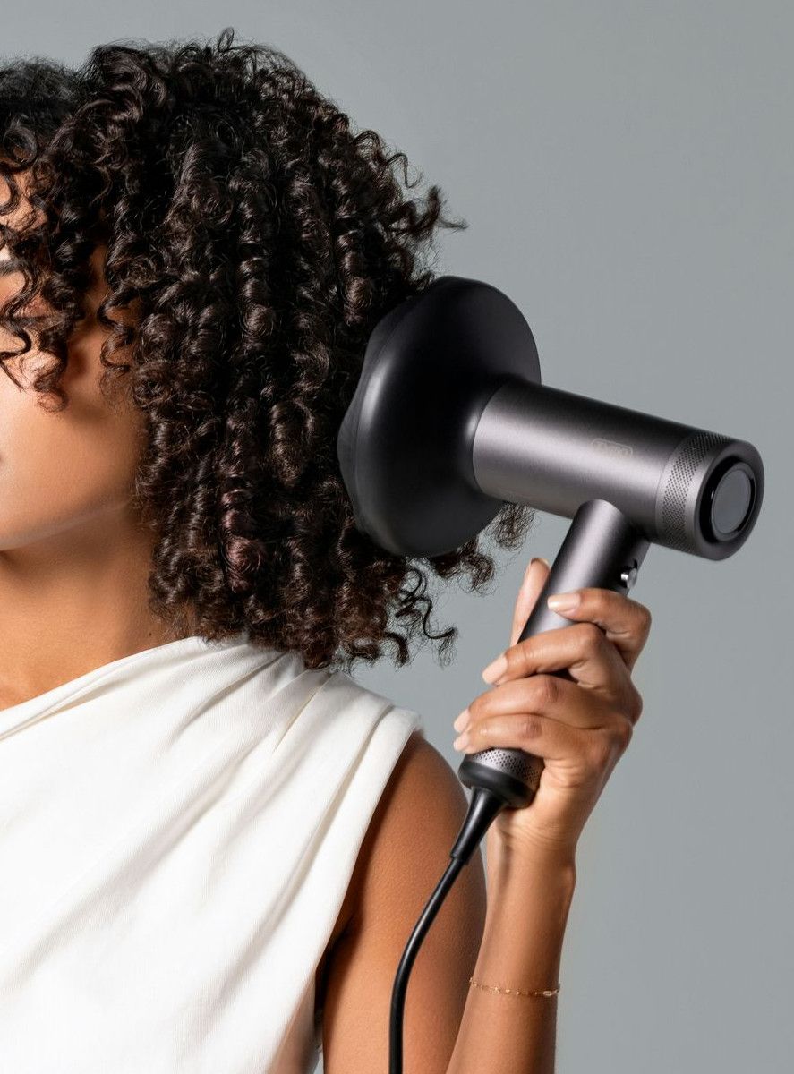 a woman blow drying her hair with a hair dryer